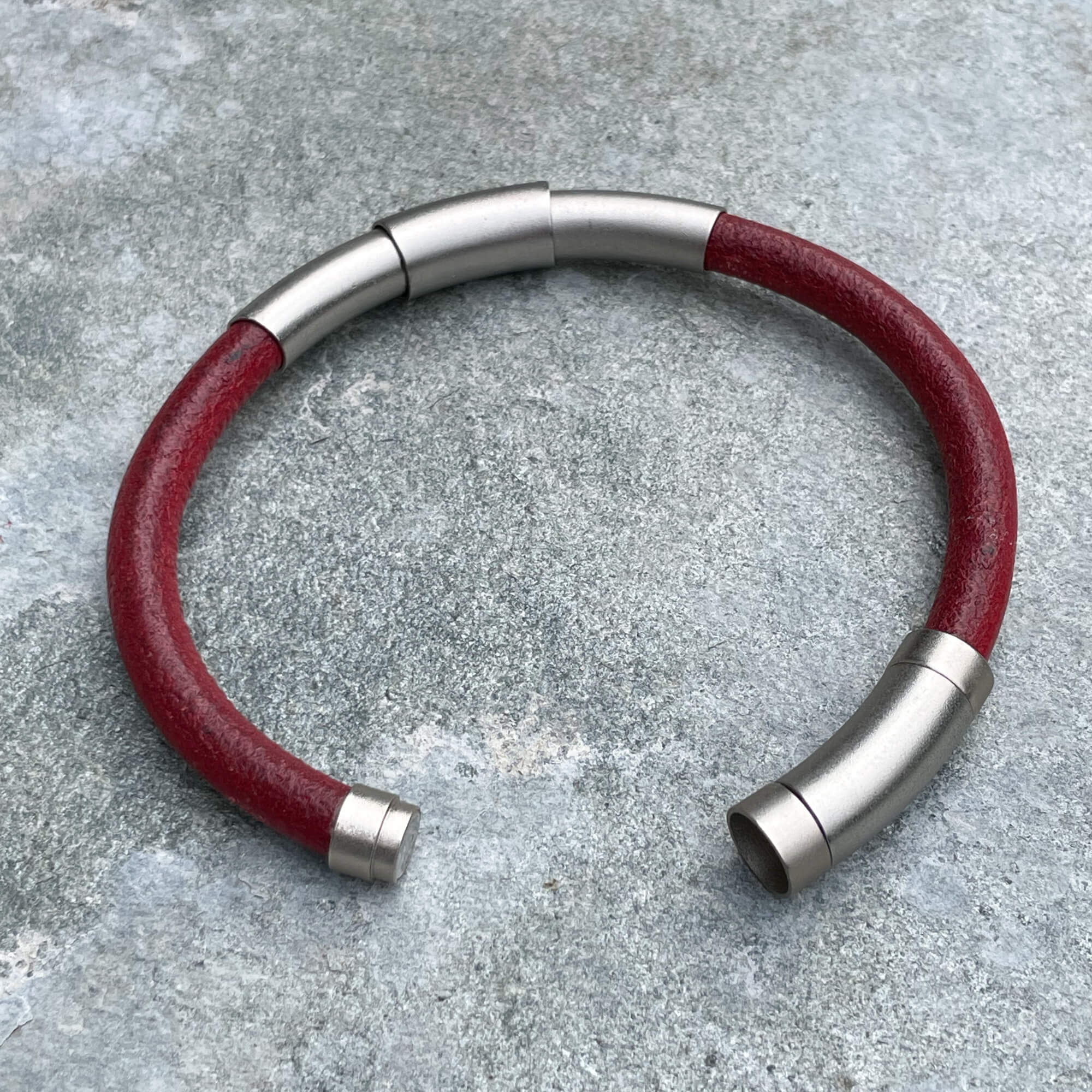 Red leather bracelet with silver colored band from stainless steel