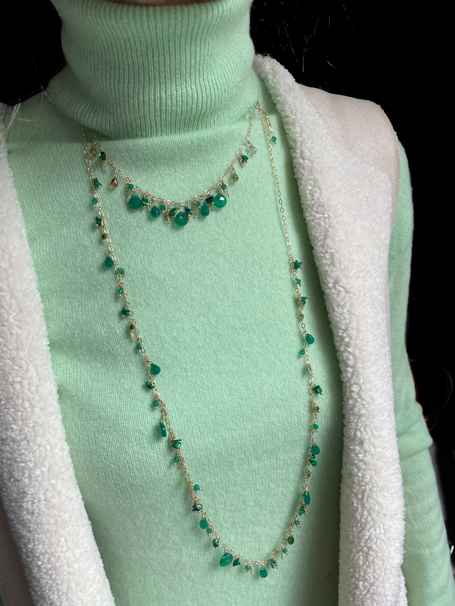 Long gold necklace with green gems
