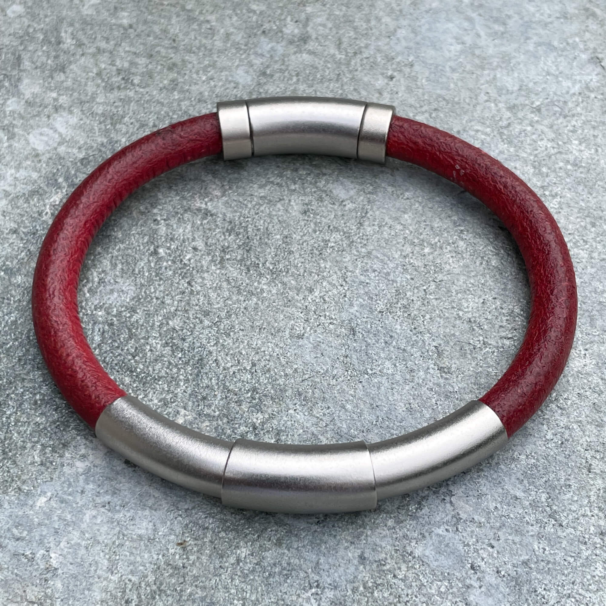 Red leather bracelet with silver colored band from stainless steel