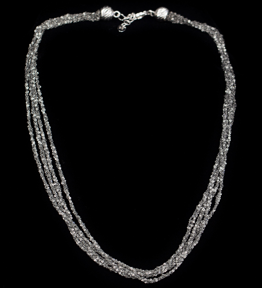 Four interwoven silver necklaces of dark grey